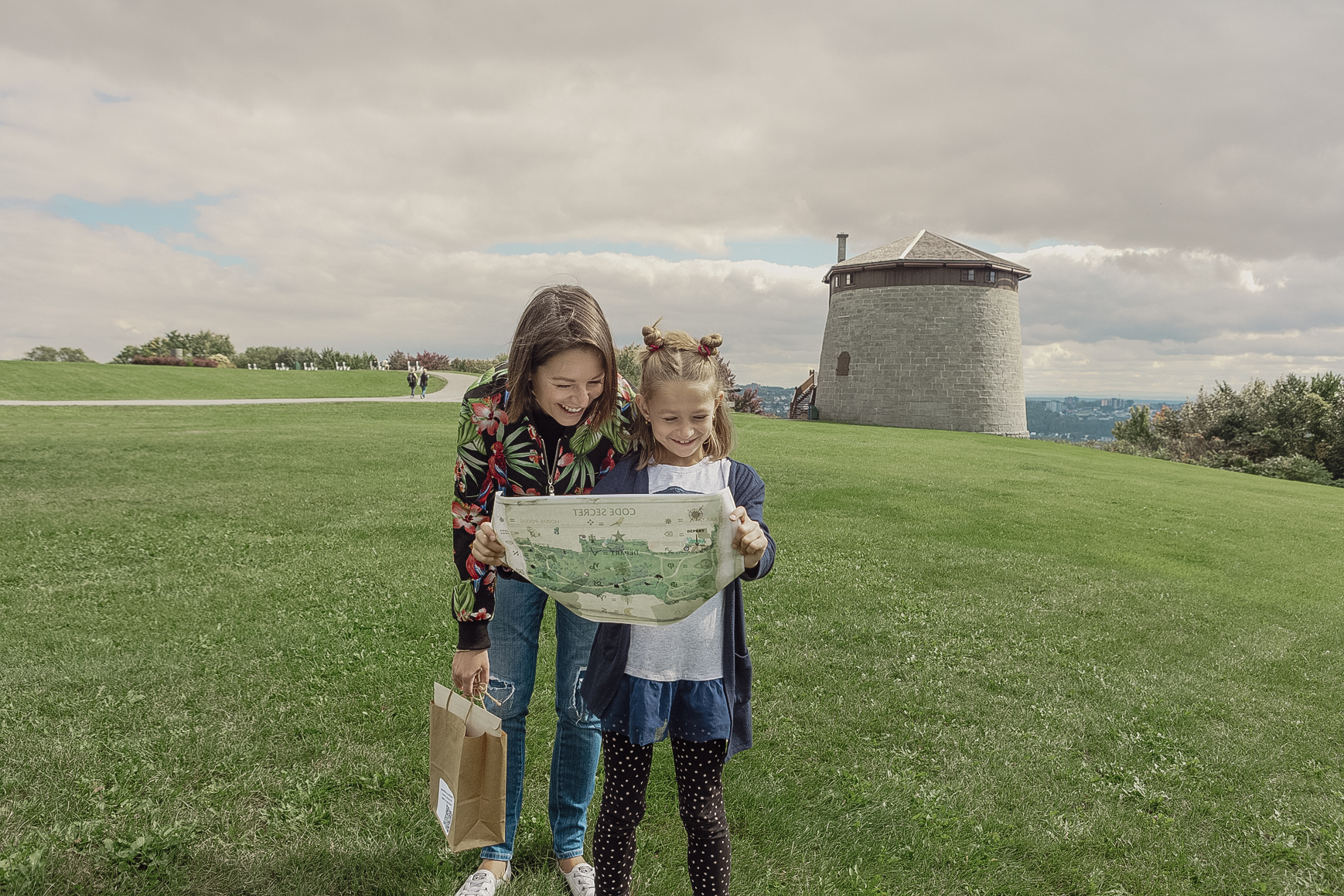 Mère et fille regardant une carte tout en souriant, près d'une tour Martello dans le parc des Plaines d'Abraham.