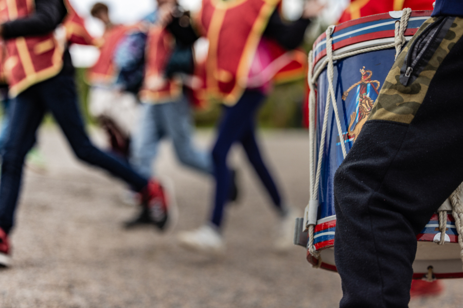 Photo de tambours et vue partielle d'élèves costumés en militaires d'époque. Photo of drums and a partial view of students dressed as historical soldiers.