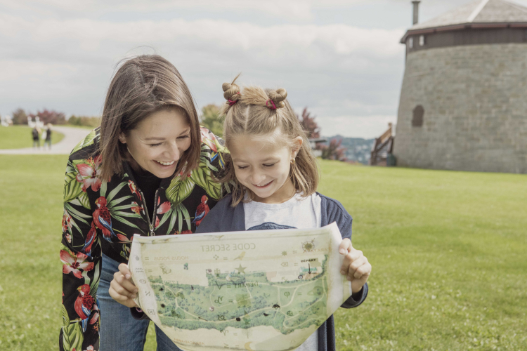 Mère et fille regardant une carte tout en souriant, près d'une tour Martello dans le parc des Plaines d'Abraham.