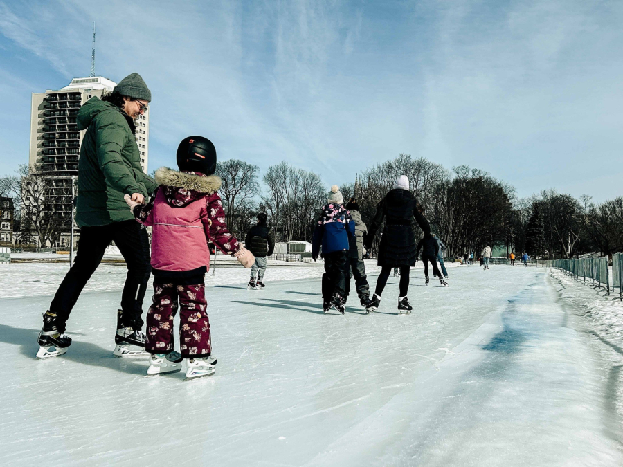 Un homme et son enfant patinant sur l'anneau de glace des plaines d'Abraham