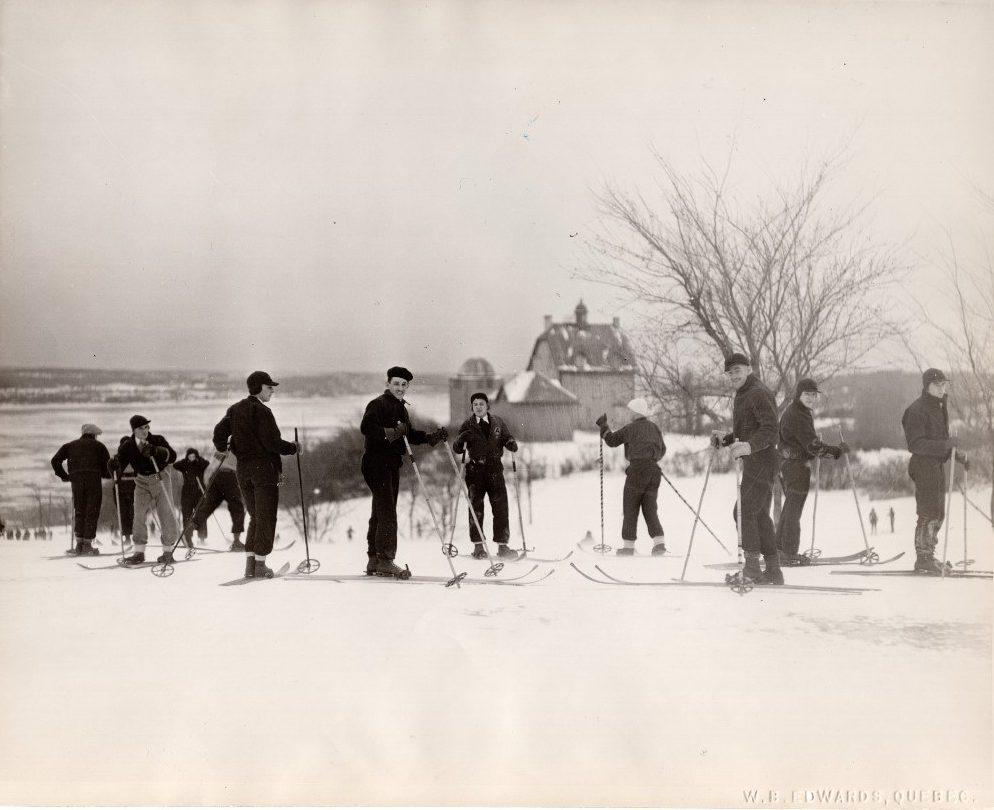 Photo d'archives montrant un groupe d'une dizaine de personnes pratiquant le ski sur les plaines d'Abraham. Archival photo showing a group of 10 people skiing on the Plains.