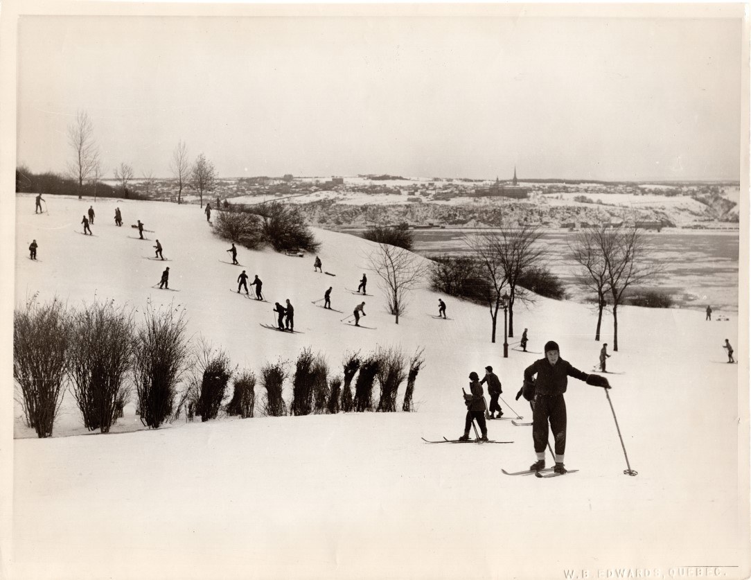 Photo d'archive où on aperçoit des skieurs dévalant une petite pente sur les plaines d'Abraham. Archive photo showing skiers descending a small slope on the Plains of Abraham.