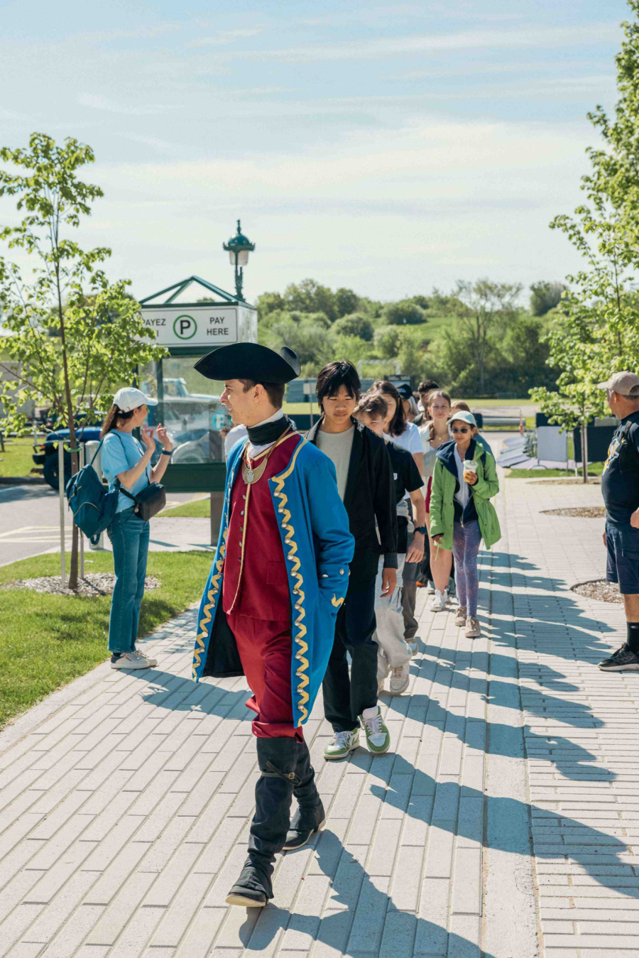 Guide-animateur portant un costume de militaire d'époque devant une file d'élèves du secondaire.
