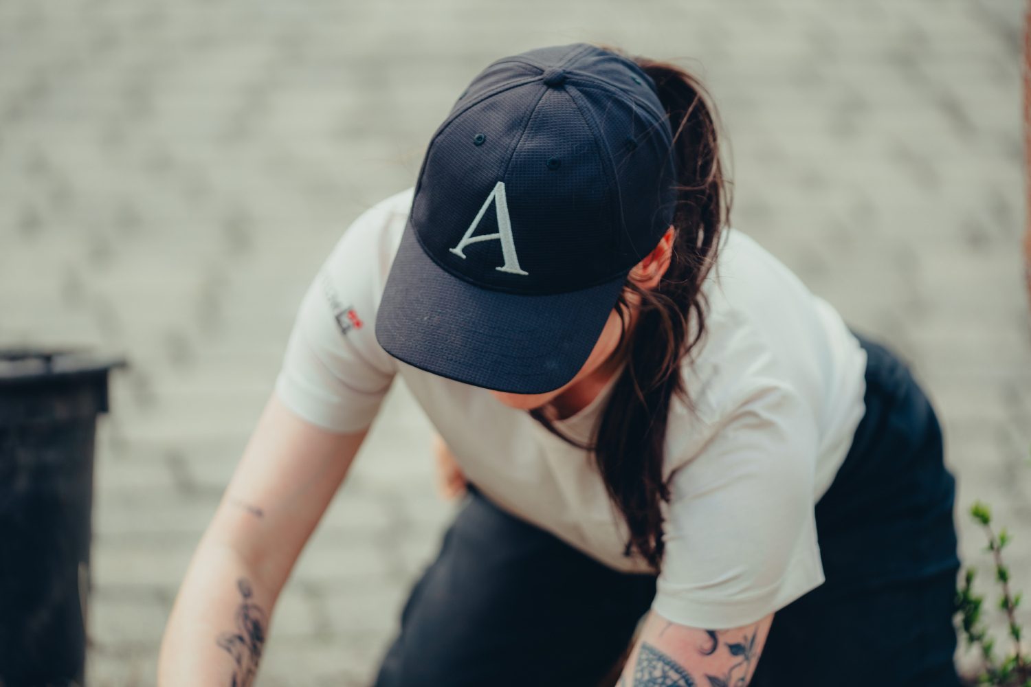 Une horticultrice portant un chandail beige et une casquette noir lettrée Plaines d'Abraham. A horticulturist wearing a beige sweater and a black cap labeled Plains of Abraham