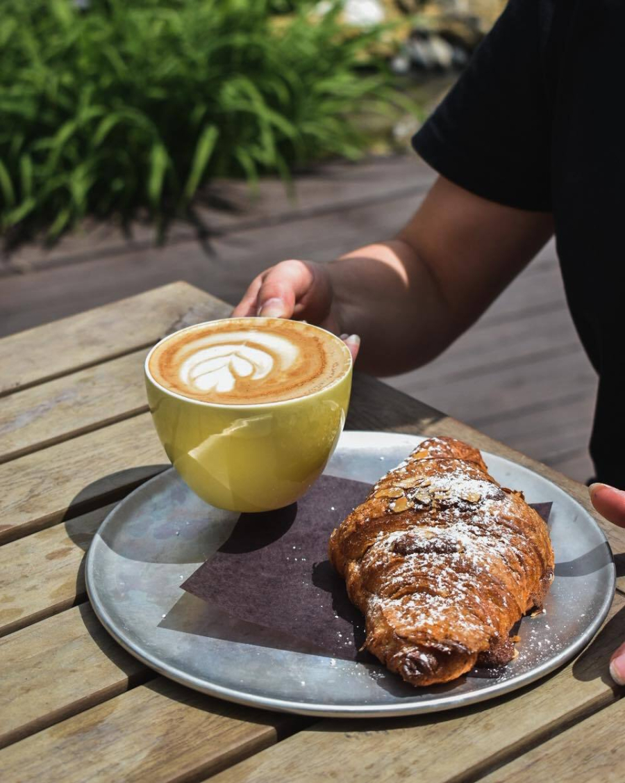 Croissant et café servi dans une grasse tasse de couleur jaune sur une table de la terrasse du Café La Maison Smith des plaines d'Abraham
