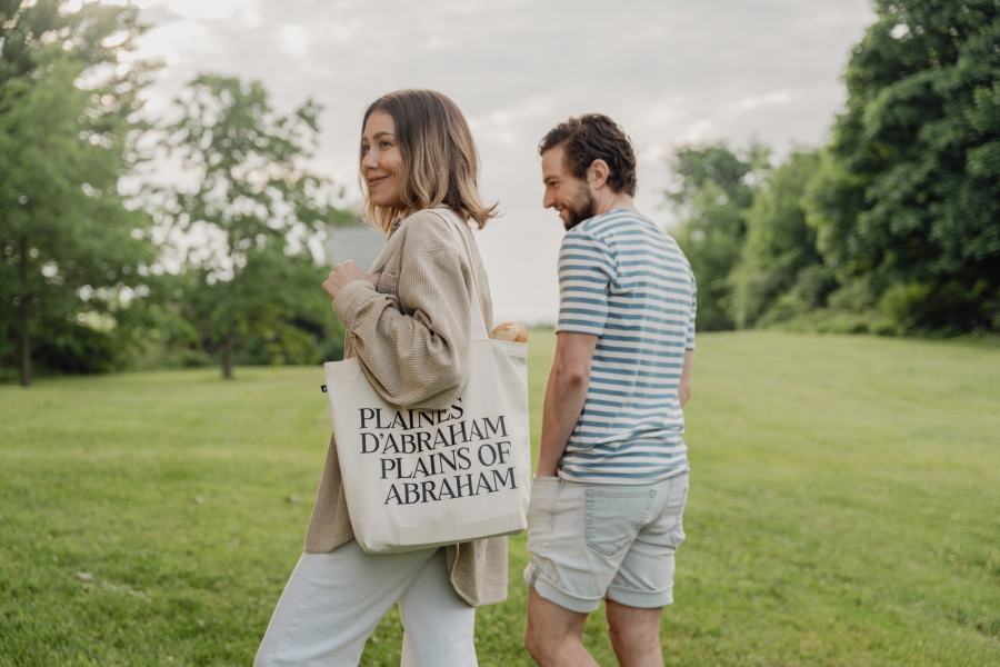 Photo of two people walking on the Plains with a bag bearing the effigy of the Plains of Abraham.