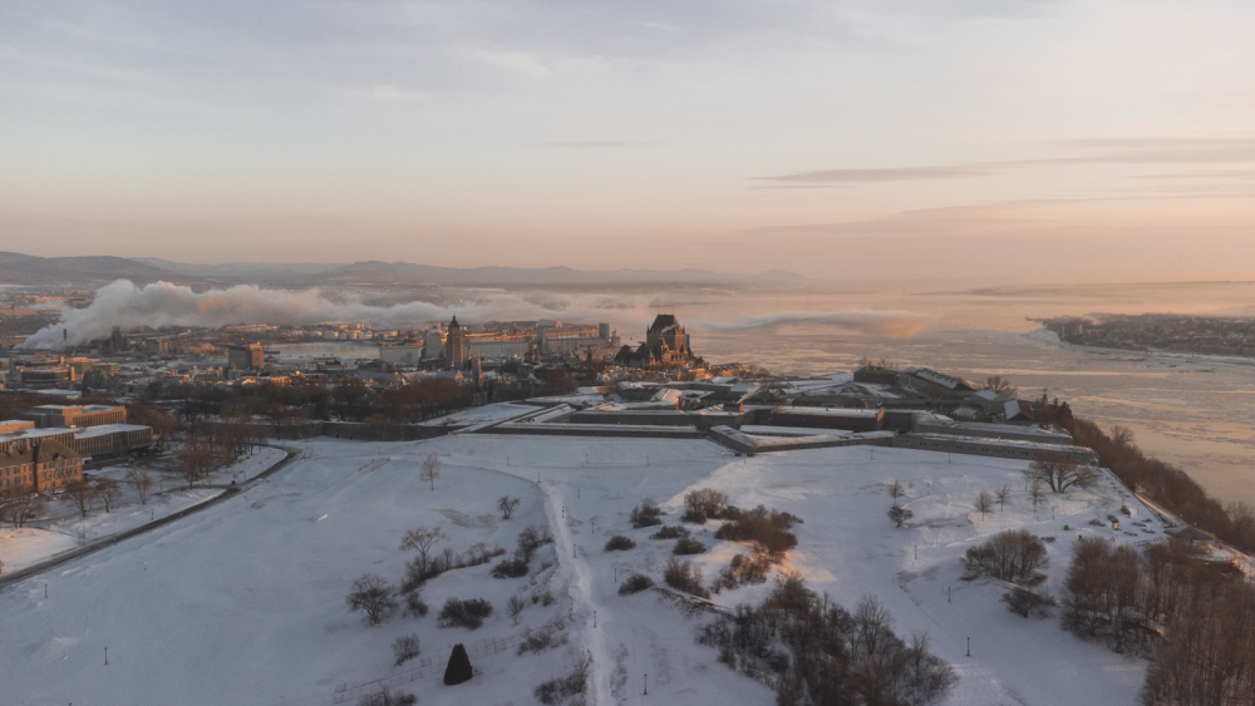 Vue aérienne en hiver des plaines d'Abraham et d'une partie du Vieux-Québec et du fleuve Saint-Laurent. Aerial view in winter of the Plains of Abraham, part of Old Québec, and the Saint Lawrence River.