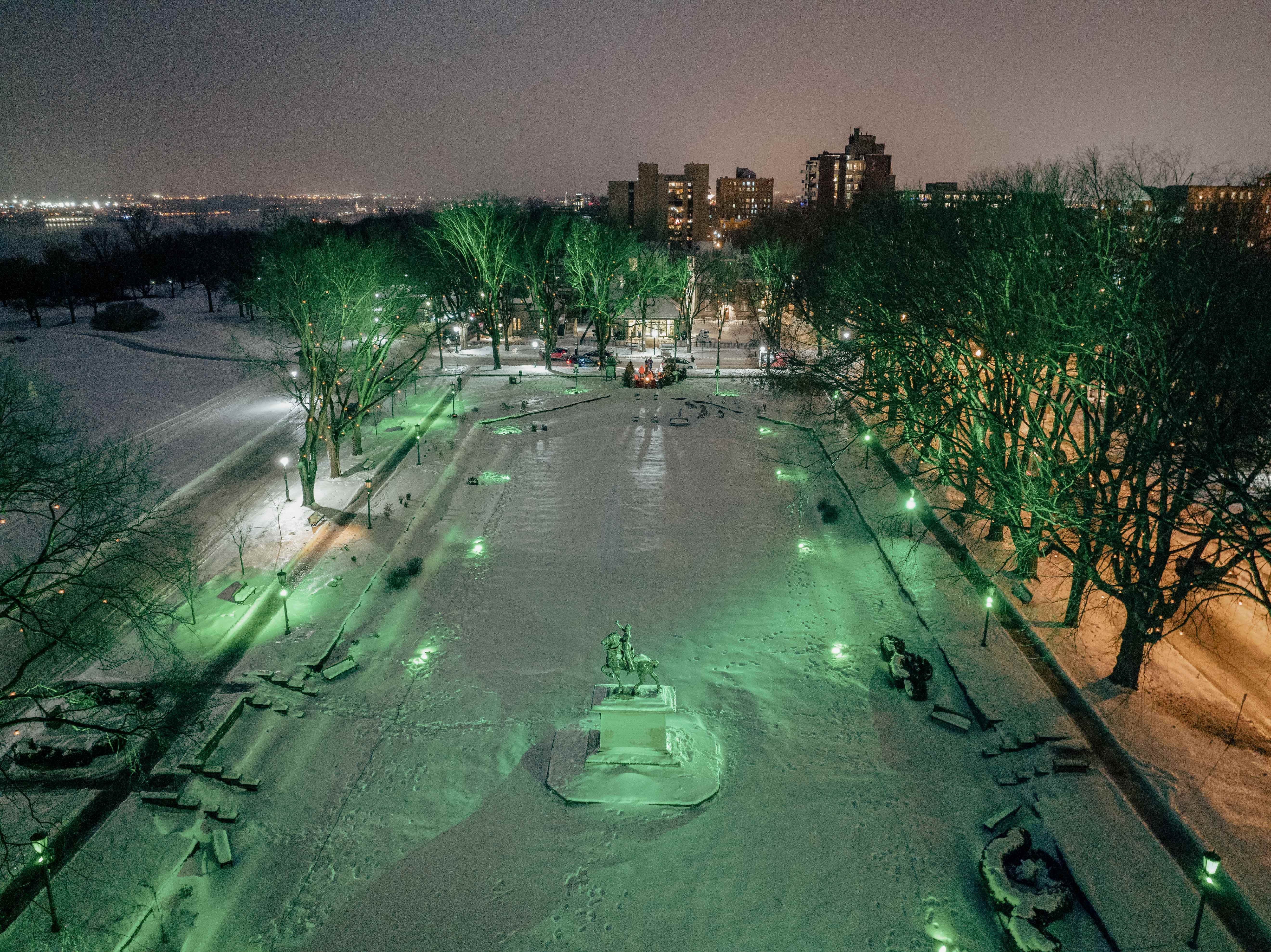 Le jardin Jeanne-d'Arc illuminé, vu des airs en hiver. On aperçoit la statue Jeanne-d'Arc au centre. The illuminated Joan of Arc Garden, viewed from above in winter, with the Joan of Arc statue at the center.