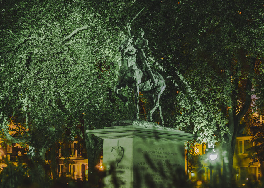 Photo de la statue Jeanne d'Arc illuminée la nuit par un éclairage extérieur.