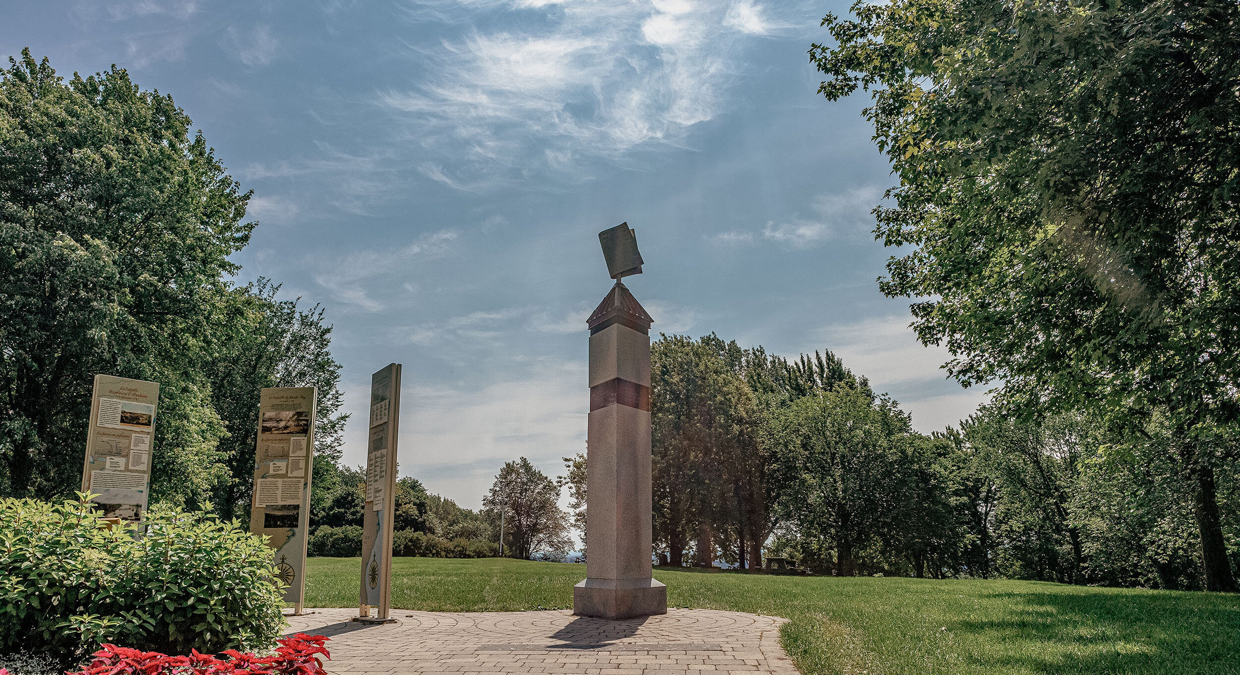 Image of the Monument to the Combatants located on the Plains of Abraham in Quebec City. The imposing monument is surrounded by greenery and is dedicated to the military and civilian fighters who took part in the battles of 1759 and 1760. Inscriptions and sculptures adorn the monument, paying tribute to the brave fighters. In the background, part of the historic park and its well-maintained paths can be seen. // Image du Monument aux Combattants situé sur les plaines d'Abraham à Québec. L'imposant monument est entouré de végétation et est dédié aux combattants militaires et civils ayant participé aux batailles de 1759 et 1760. Des inscriptions et des sculptures ornent le monument, rendant hommage aux courageux combattants. En arrière-plan, on aperçoit une partie du parc historique et ses sentiers bien entretenus.