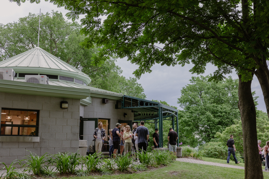 Des visiteurs sont devant le bâtiment du Café Maison Smith. 
Visitors are standing in front of the Maison Smith Café building.