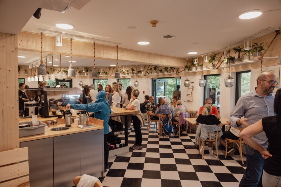 Intérieur du nouveau café La Maison Smith des plaines d'Abraham, sol en carrelage noir et blanc et mur en bois. Interior of the new La Maison Smith café on the Plains of Abraham, featuring a black-and-white tiled floor and wooden walls.