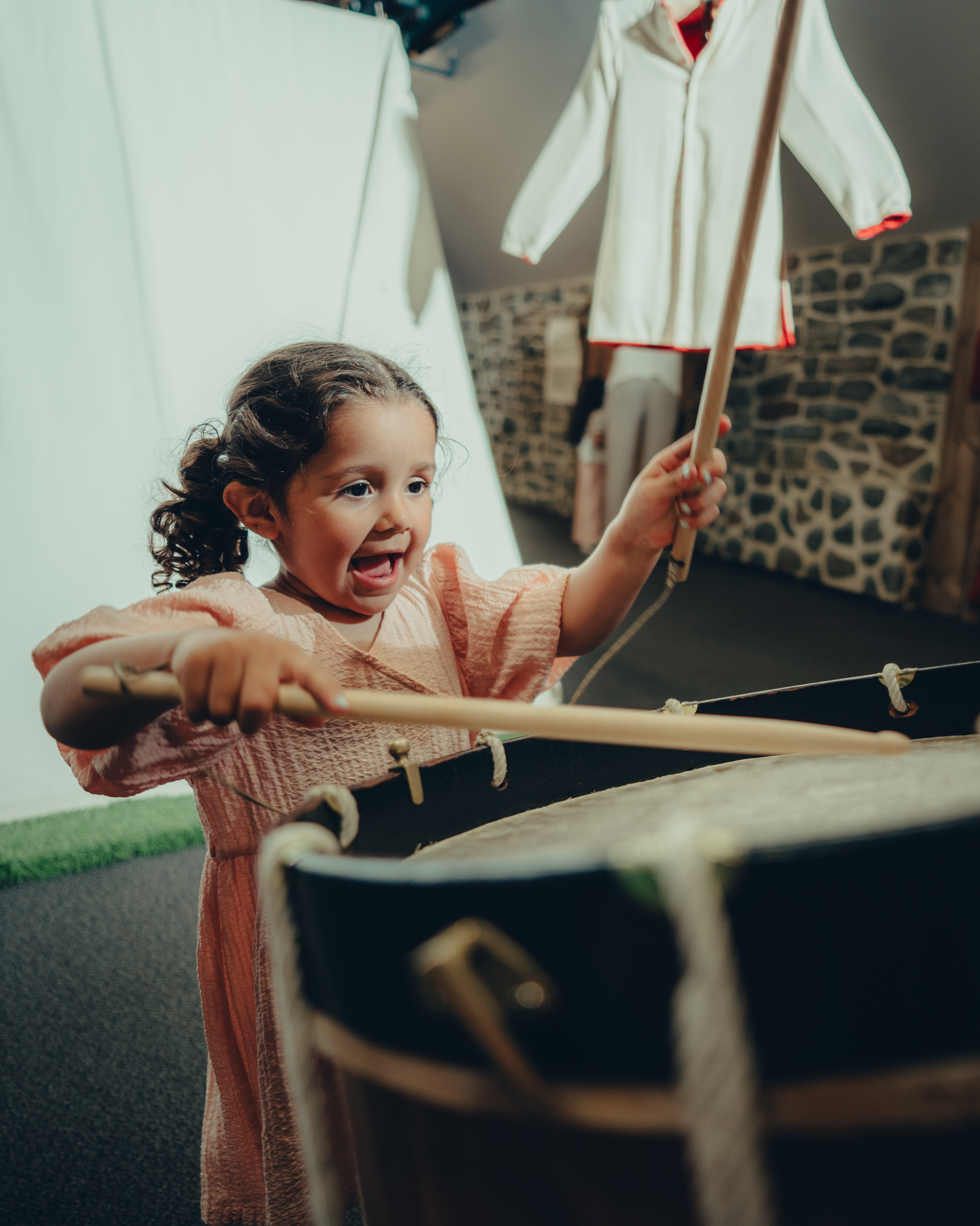 Photo d'une fillette jouant avec des objets anciens en exposition au Musée des plaines d'Abraham. Photo of a young girl playing with historical objects on display at the Plains of Abraham Museum.