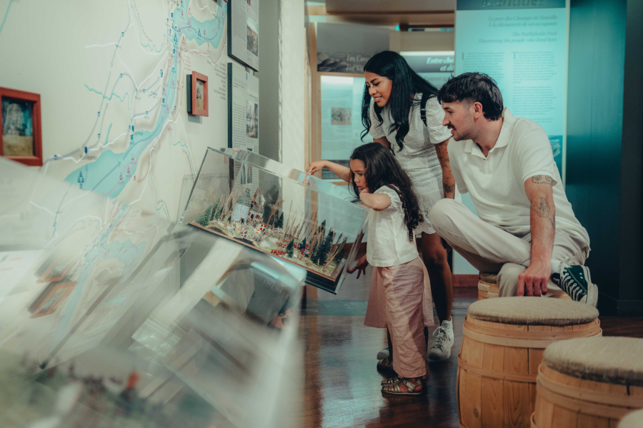 Photo d'une famille admirant une exposition au Musée des plaines d'Abraham. Photo of a family admiring an exhibit at the Plains of Abraham Museum.